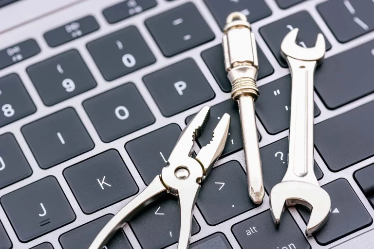 wrench, screwdriver and pliers laying on laptop keyboard